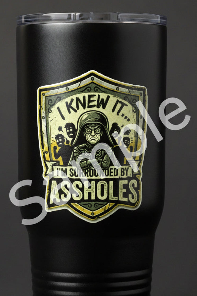 Sticker with text 'I knew it, I'm surrounded by assholes' on a shield design with a character and people in the background.