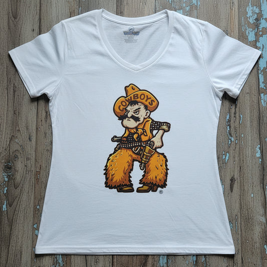 A white women's V-neck t-shirt featuring University of Wyoming Cowboy Joe graphic on a white fabric background. The cowboy wears a yellow hat with the word 'COWBOYS' and a matching bandana, with yellow furry chaps and boots, holding a gun, laid flat on a gray wood plank background.