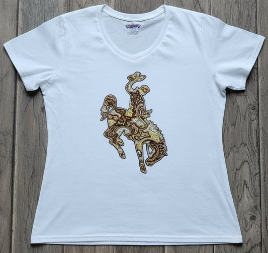 A white short-sleeve V-neck t-shirt featuring a graphic print of Wyoming bucking horse logo in a brown, yellow and white paisley pattern on white fabric. The shirt is laid flat on a gray wooden plank surface.
