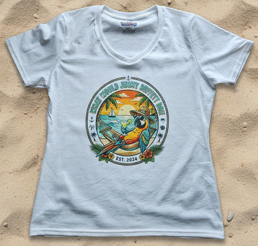 A white V-neck t-shirt laid flat on a sandy background, featuring a colorful circular graphic print of a parrot, tropical beach scene, and the text 'What would Jimmy Buffet do!'