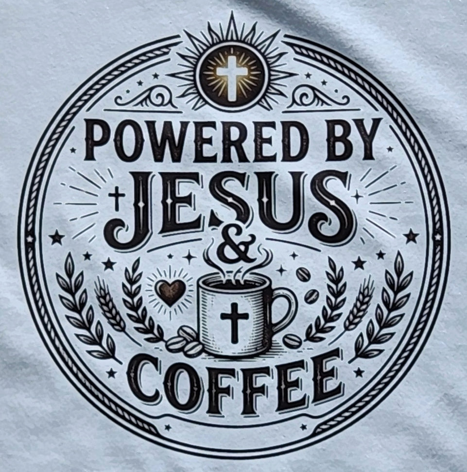 A close-up of a circular printed graphic on a white fabric, featuring the text 'POWERED BY JESUS & COFFEE' with a cross, coffee mug, coffee beans, and decorative flourishes.