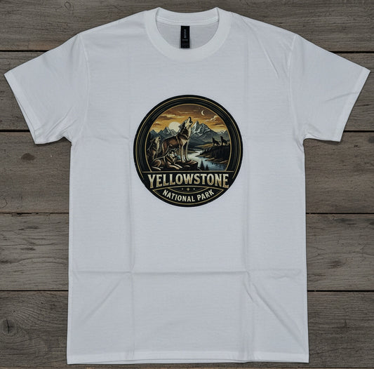 A white short-sleeve crewneck t-shirt laid flat on a rustic gray-brown wooden plank background. The center of the shirt features a circular graphic print depicting a Wolf in Yellowstone National Park, with 'YELLOWSTONE NATIONAL PARK' printed below the illustration.