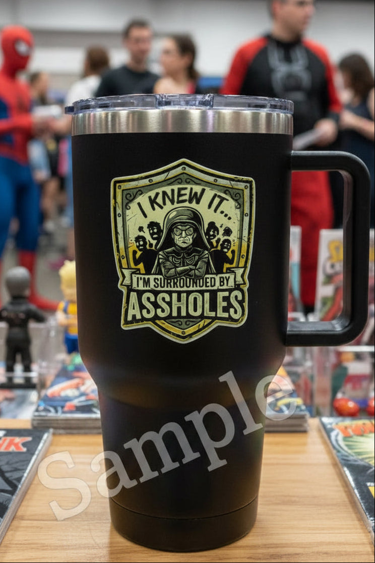 Sticker with a graphic of a character and text 'I knew it... I'm surrounded by assholes' on a shield-like border.