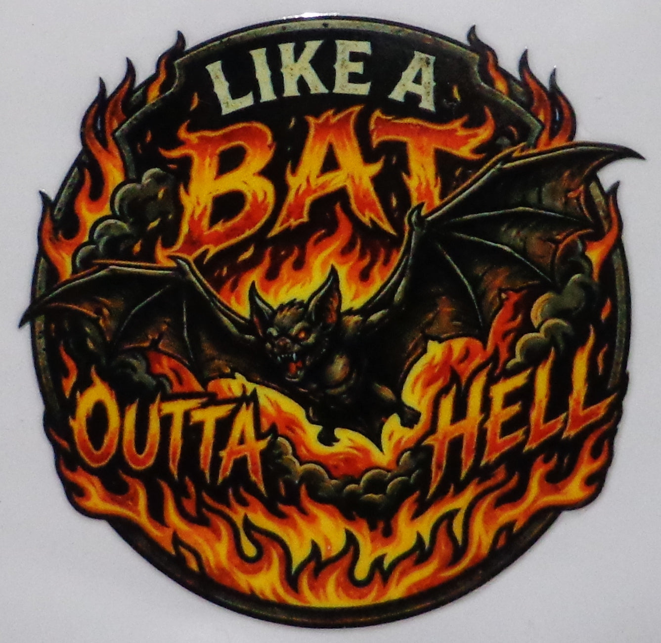 A circular graphic sticker or decal featuring a black bat surrounded by orange and yellow flames, with the text 'LIKE A BAT OUTTA HELL' in stylized lettering.