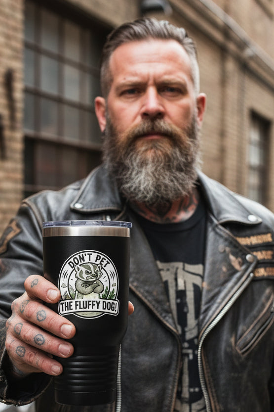 A circular sticker or decal featuring a cartoon badger with crossed arms and the text 'DON'T PET THE FLUFFY DOG!' in bold black lettering on a white background. Held by a man in a leather jacket. 