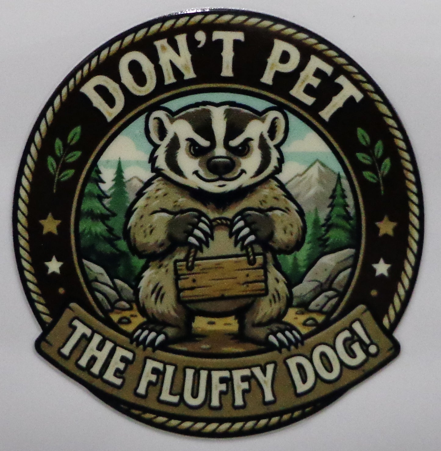 A circular novelty sticker featuring a cartoon badger, with the text 'DON'T PET THE FLUFFY DOG!' around the design.