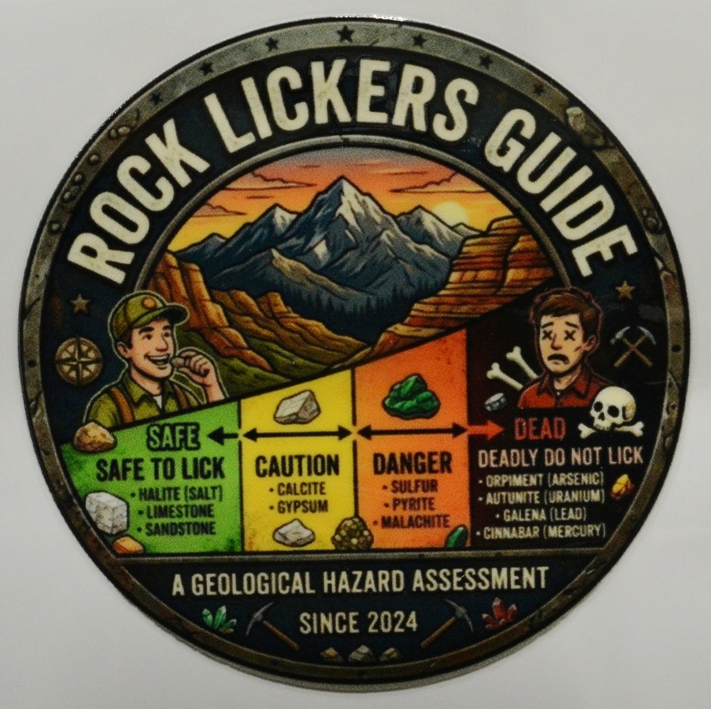 Circular sign titled 'Rock Lickers Guide' with a mountain landscape and color-coded chart of dangers