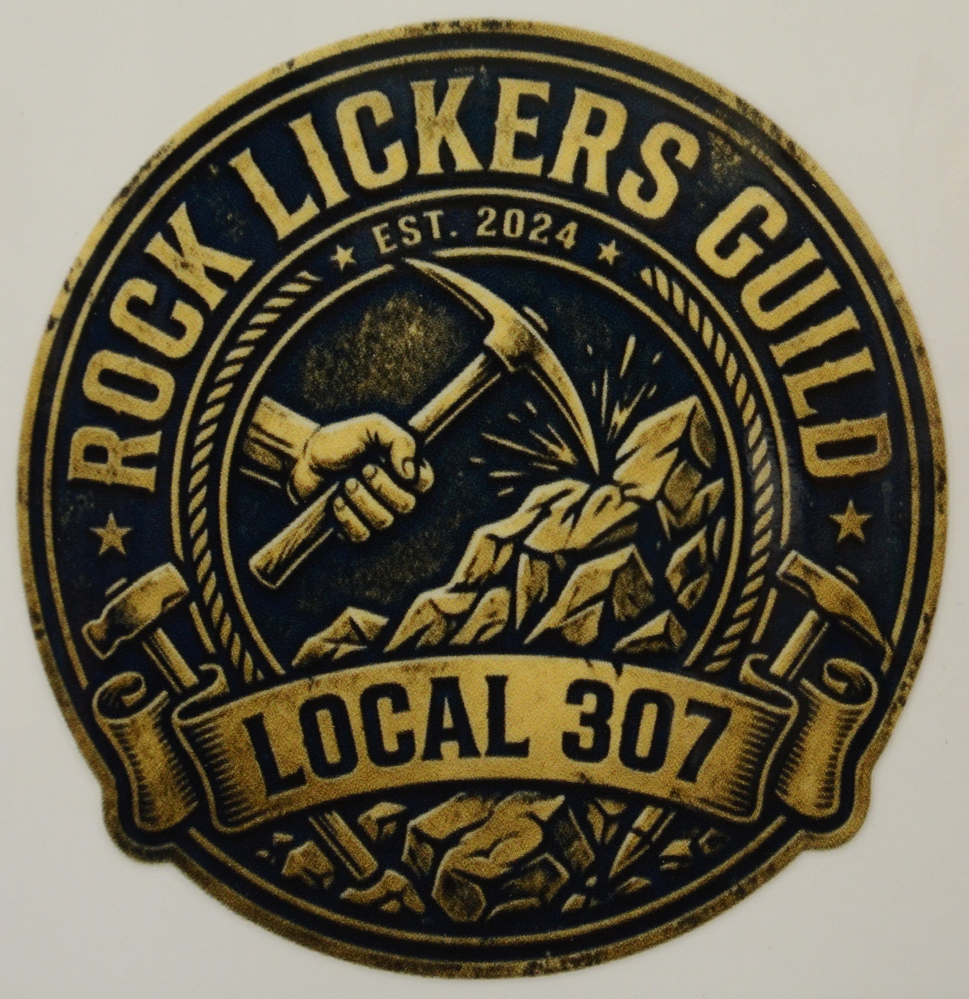 Logo of Rock Lickers Guild Local 307 with a hammer and mountain design on a black background.